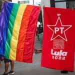 A rainbow flag, a red flag for Lula from the Worker’s Party and a pink flag hang in a row.