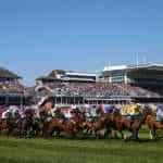 A general view of horses and riders taking the first bend at Aintree Racecourse.