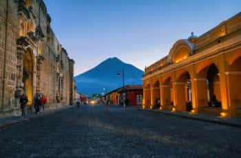 Old fashioned buildings with a mountain in the background in Bulevar Villa Deportiva, Guatemala.