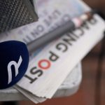 A Racing TV microphone sits on a Racing Post newspaper.